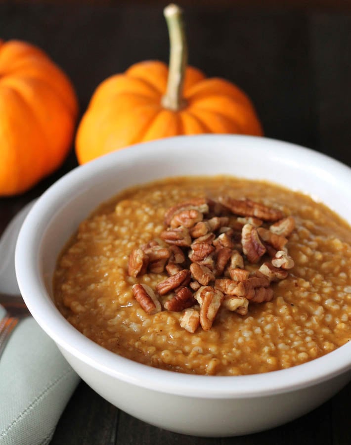 A bowl of Pumpkin Steel Cut Oats sitting on a dark wood table.