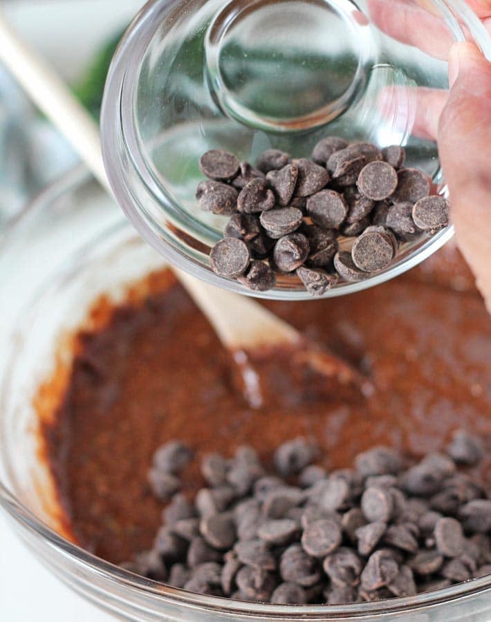 Chocolate chips being poured into the batter for Vegan Gluten Free Chocolate Zucchini Muffins.