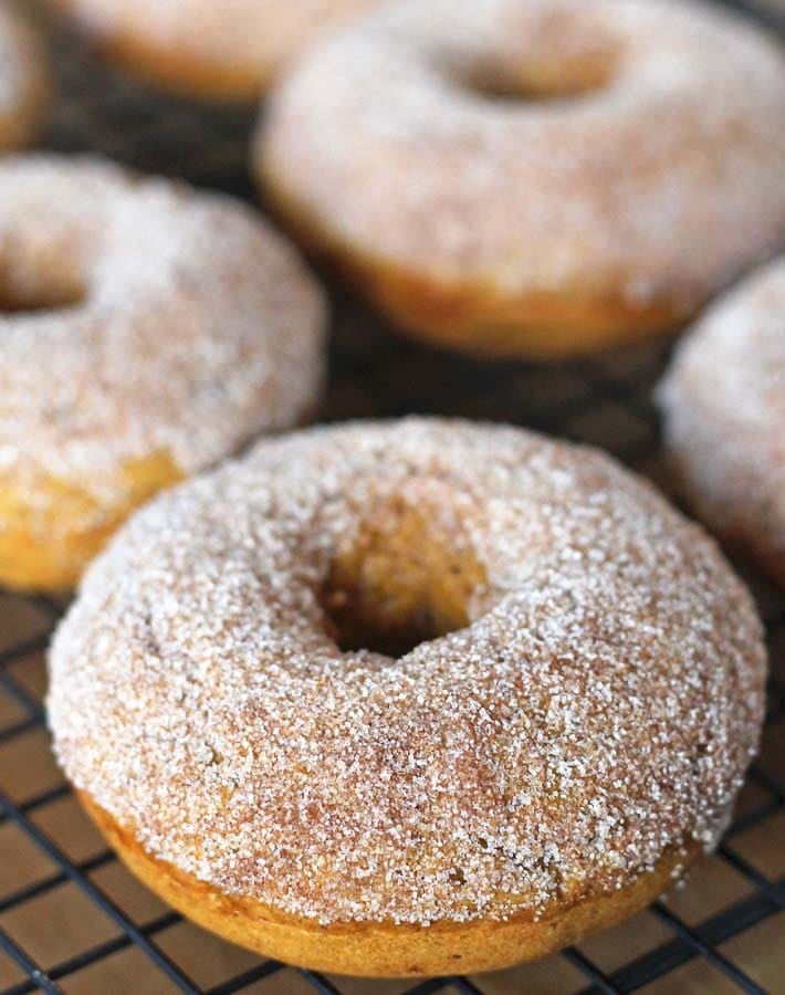 Vegan Baked Pumpkin Doughnuts on a cooling rack, doughnuts have been dusted with sugar.