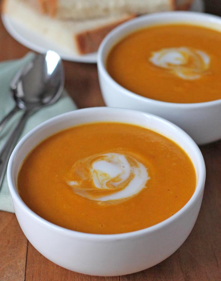 Close up shot of two bowls of Cauliflower Sweet Potato Soup in white bowls.