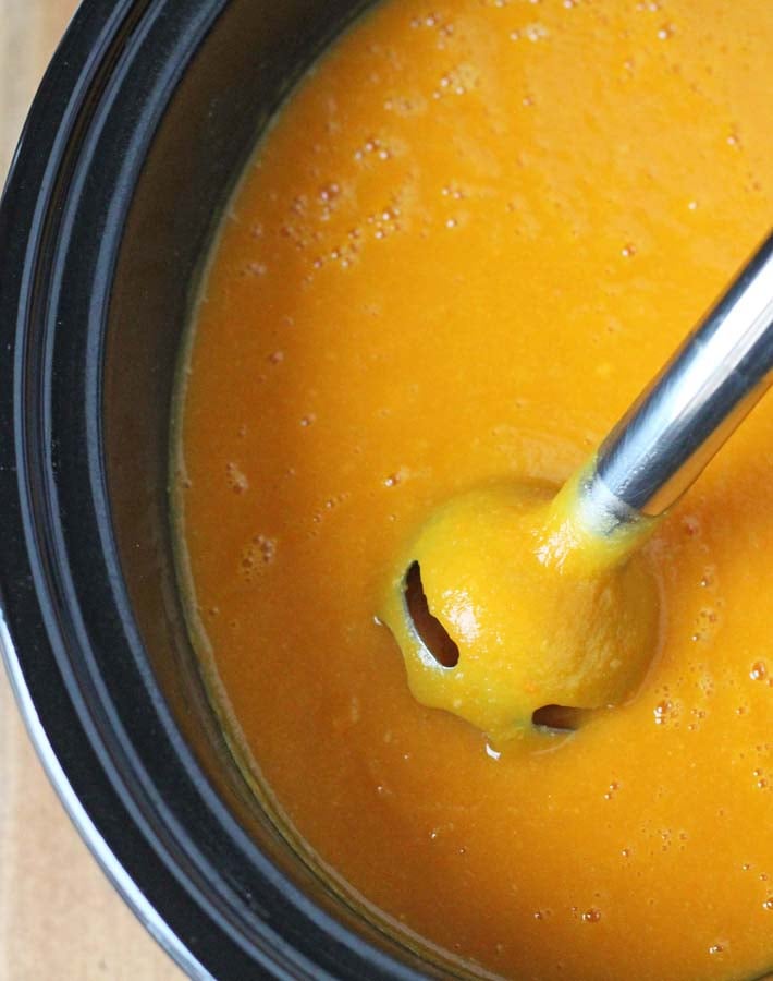 Cauliflower Sweet Potato Soup after being pureed, hand blender is still in the slow cooker.