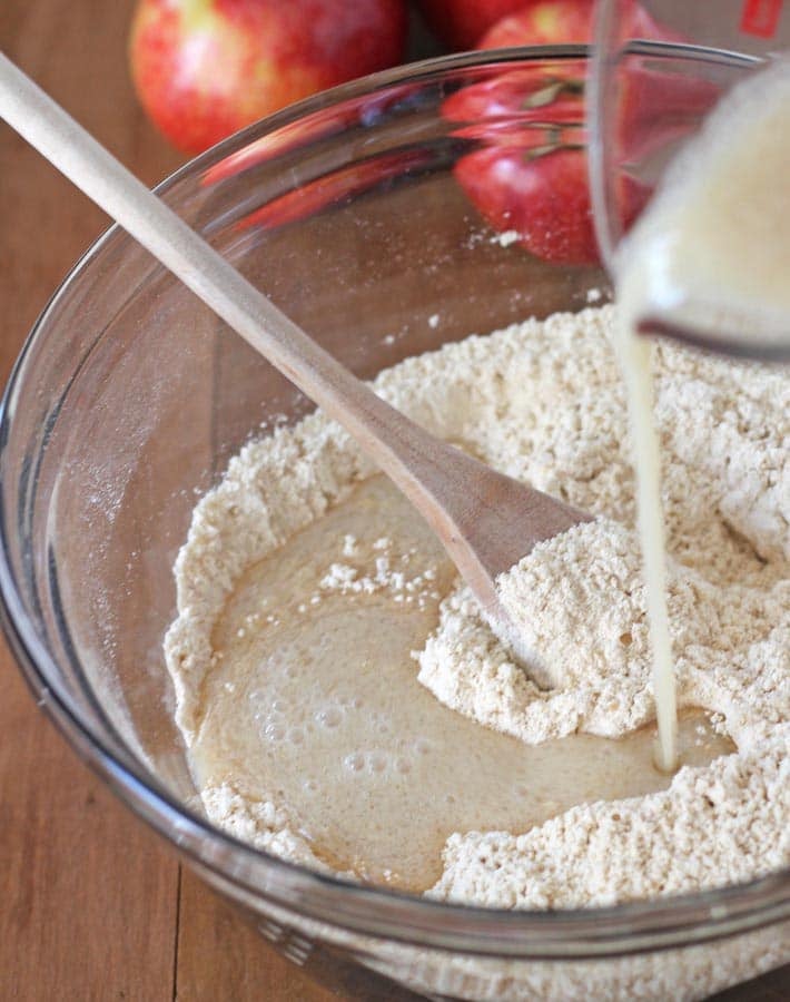 Wet ingredients being poured into dry ingredients to make the batter for Gluten Free Vegan Apple Muffins.