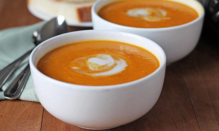 Cauliflower Sweet Potato Soup in white bowls on a brown wood table.