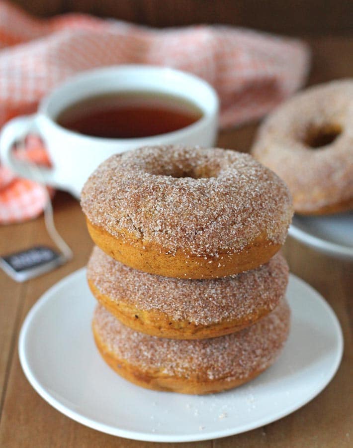 A stack of three Vegan Baked Pumpkin Doughnuts on a white plate.