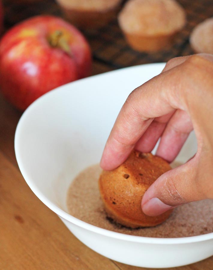 Gluten Free Vegan Apple Muffins being dipped in cinnamon sugar.