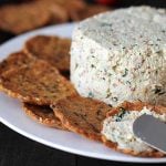 Close up shot of garlic herb vegan almond cheese spread onto a cracker.