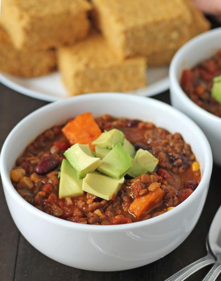 Lentil Sweet Potato Chili topped with diced avocado in a white bowl.