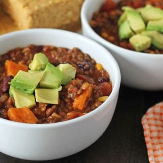 Lentil Sweet Potato Chili in a white bowl on a dark wooden table.