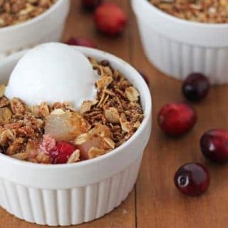 Pear Cranberry Crisp in a ramekin on a brown table.