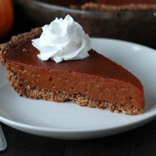 A close up shot of a slice of Vegan Sweet Potato Pie, pie has a dollop of coconut whipped cream on top.
