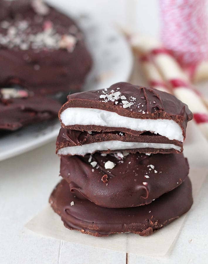 A stack of Vegan Peppermint Patties the one on top is cut in half to show the inside.