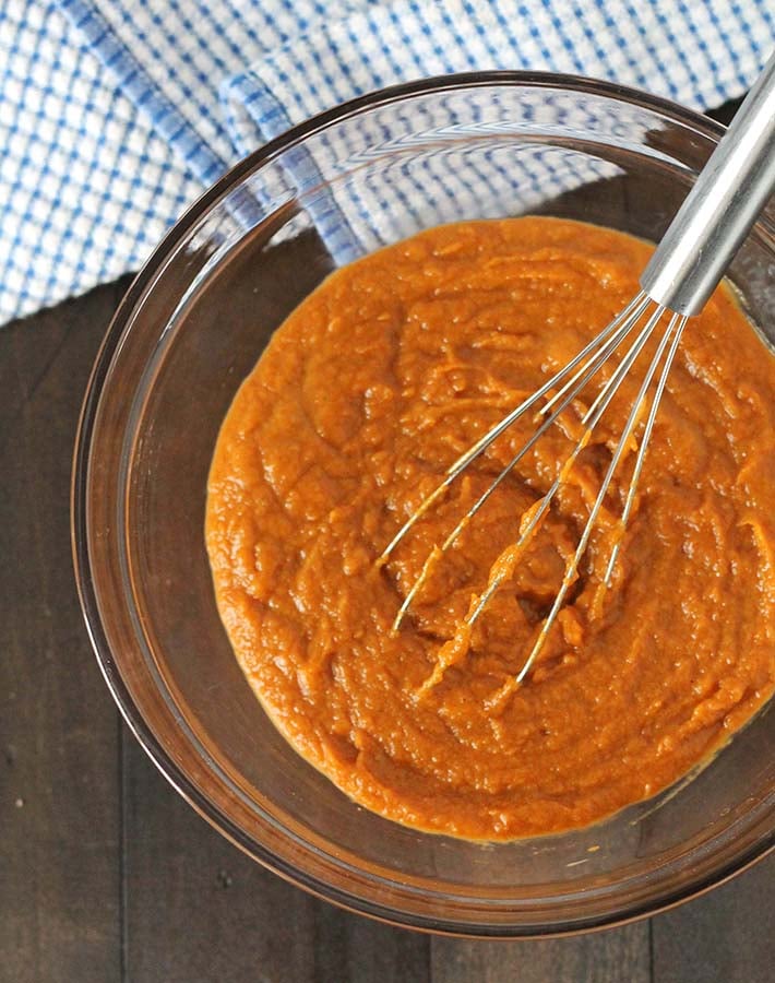 The mixture for Vegan Sweet Potato Pie in a glass bowl, a wire whisk is also in the bowl.