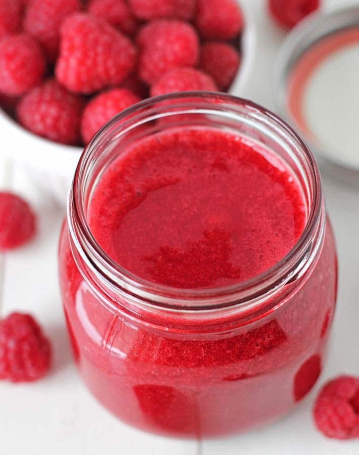 Overhead shot of a mason jar filled wtih freshly made easy raspberry sauce.