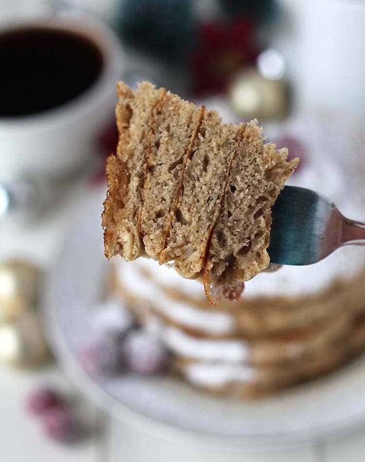 Close up shot of the inside of a stack of eggnog pancakes on a fork to show the fluffy insides.