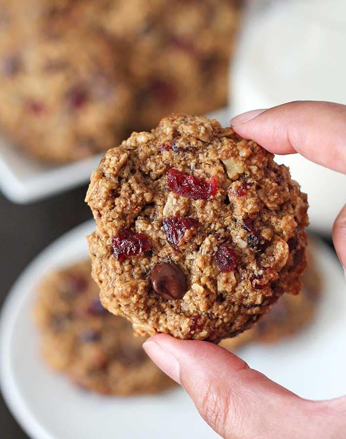Close up shot of a hand holding a Oatmeal Cranberry Chocolate Chip Cookie.