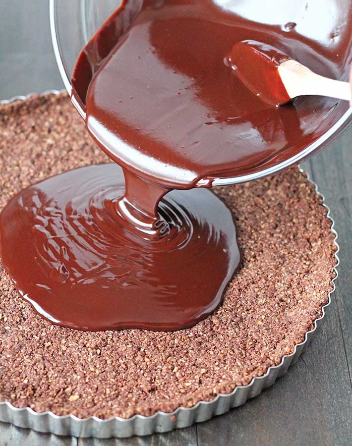 The filling for a vegan chocolate tart being poured into the tart crust.