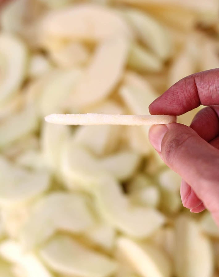 A close up shot of a slice of apple to show the thickness the apples need to be sliced to make baked cinnamon apple slices. 