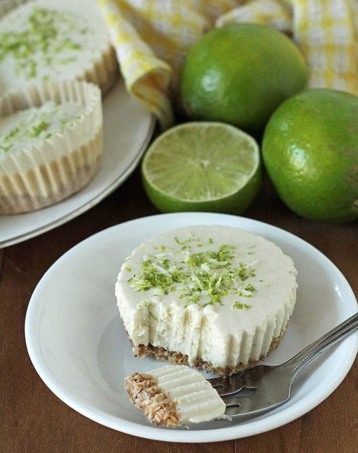 Vegan Lime Cheesecake on a plate witha piece taken out of it, piece is on a fork that also sits on the plate.