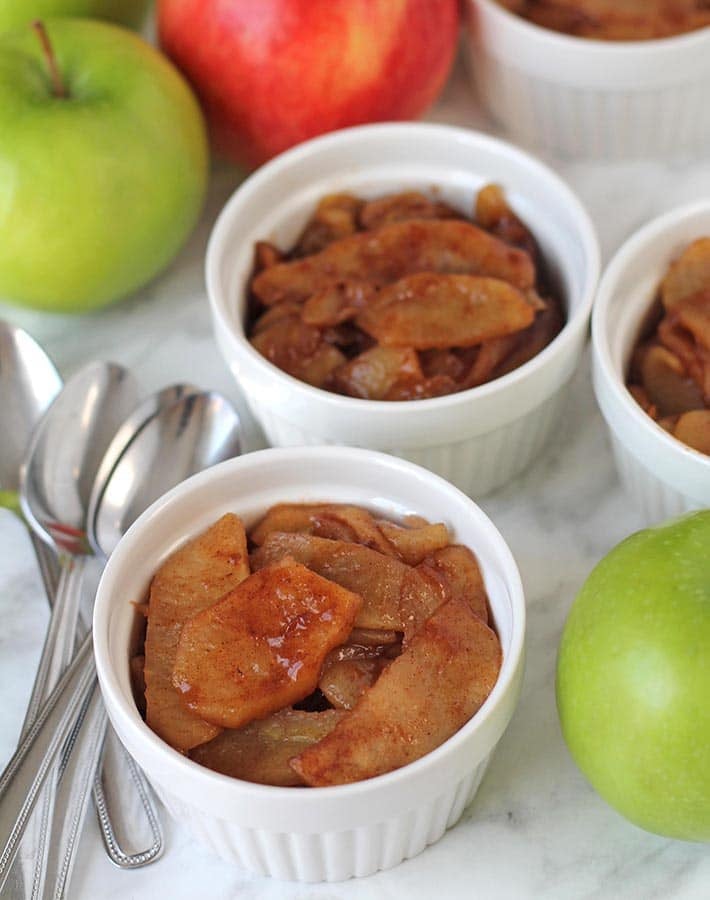 Small ramekins filled with baked cinnamon apple slices.