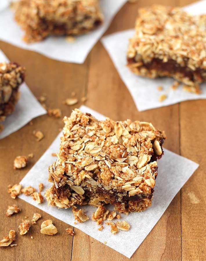 Four vegan date squares on a brown table.