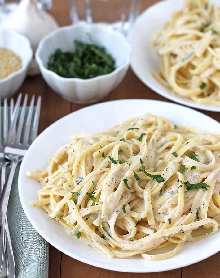 Vegan Garlic Pasta Sauce in a dish to be served, two forks sit to the left of the dish.