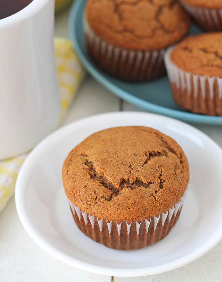 Vegan Gluten Free Banana Muffins on two plates, plates are sitting on a white table, a mug of tea sits to the left.