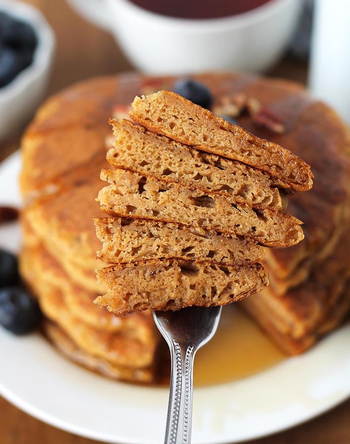 A fork holding cut pieces of Gluten Free Sweet Potato Pancakes to show the fluffy insides.