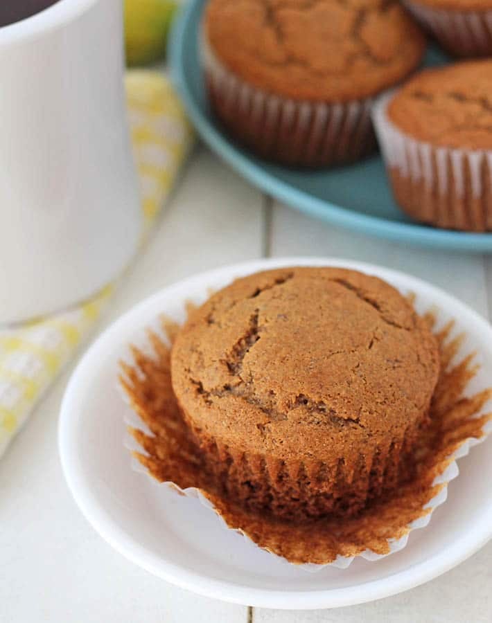 Vegan Gluten Free Banana Muffins on a blue plate, one muffin sits in front on a white plate.