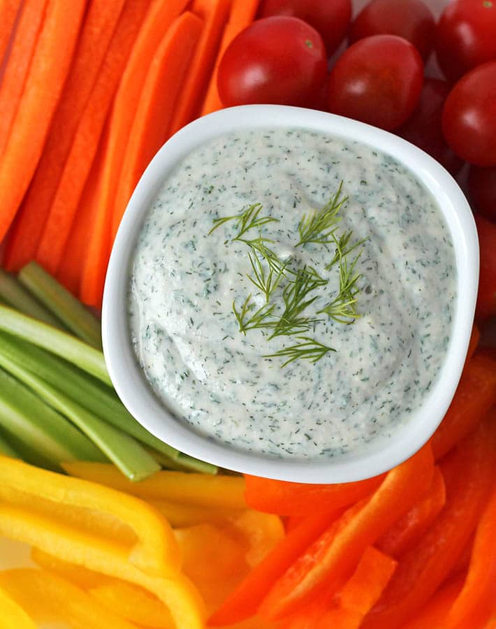 A bowl of vegan veggie dip surrounded by fresh veggies.