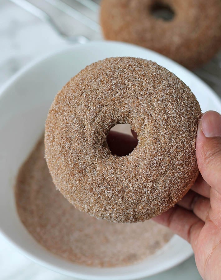 Cinnamon Sugar Vegan Doughnuts being dipped in cinnamon sugar.