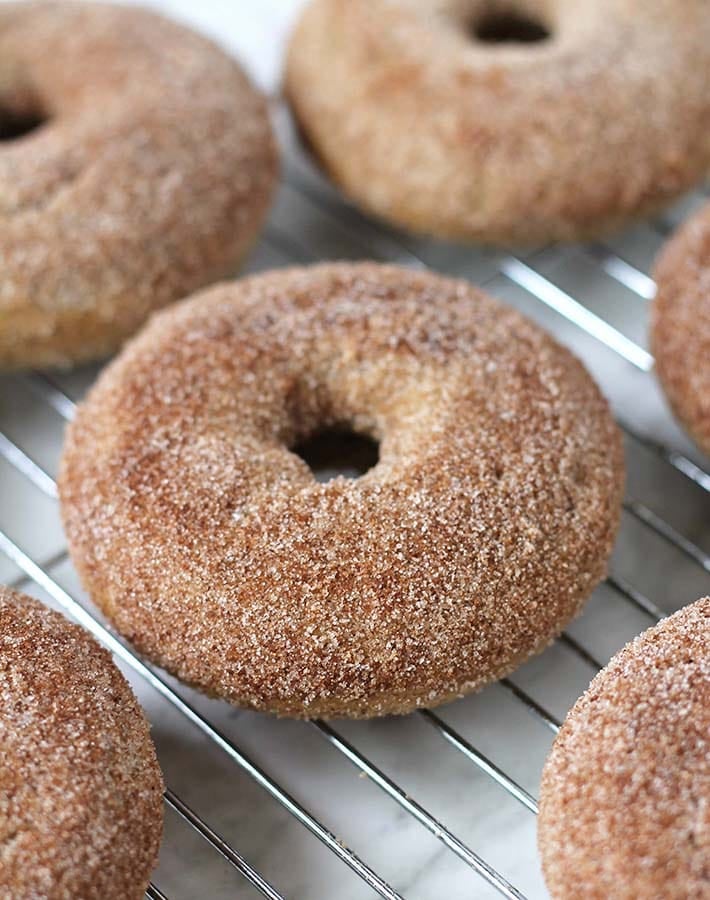 Vegan Cinnamon doughnuts on a cooling rack.