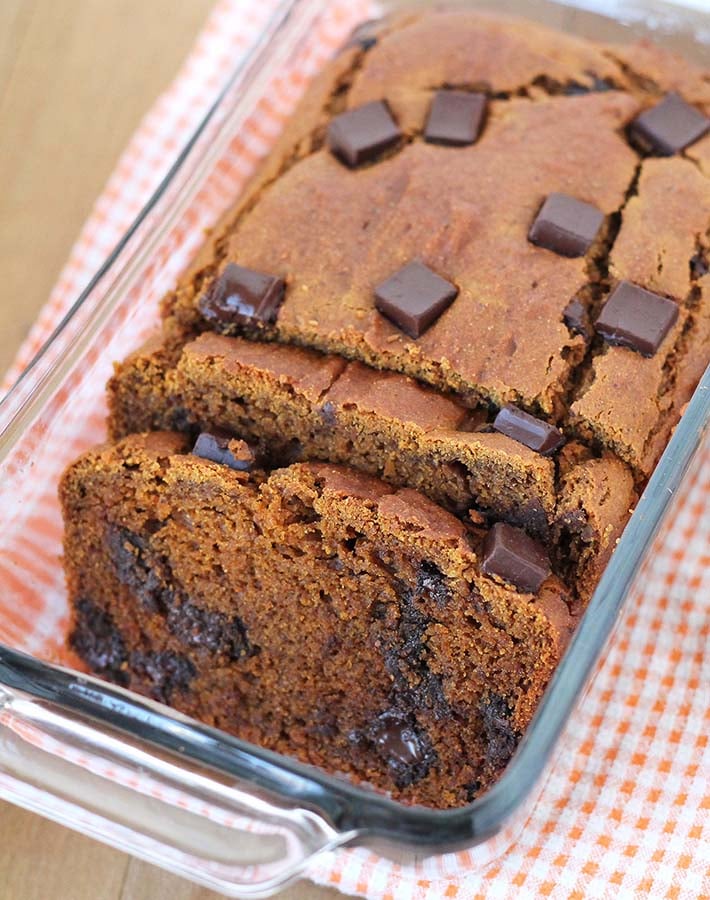 A loaf of gluten free sweet potato bread in a dish with two pieces sliced.