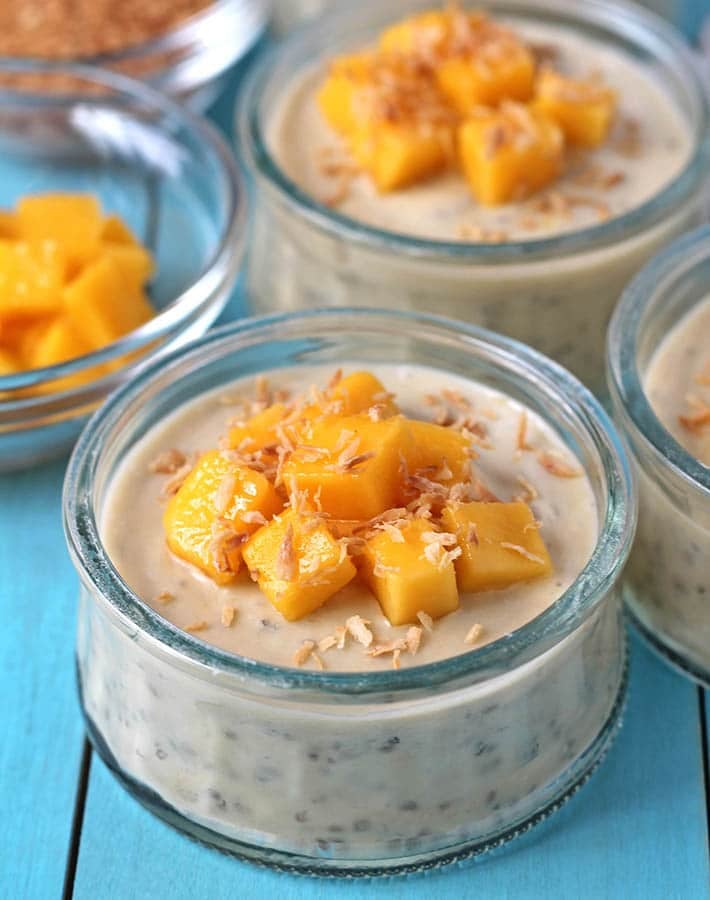 A cup of mango coconut chia pudding topped with fresh mango cubes and toasted coconut.