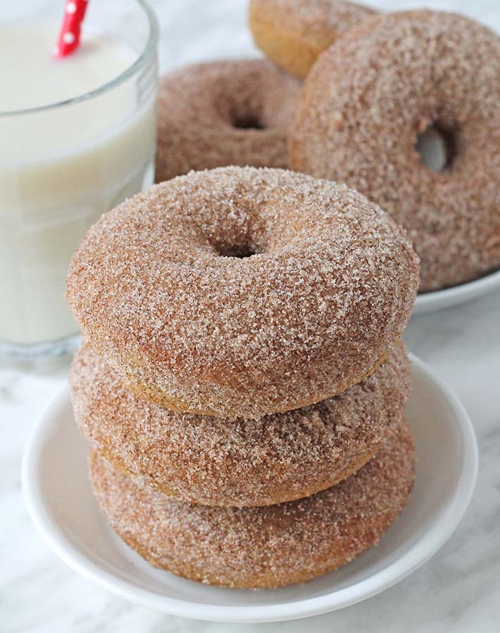 Three vegan cinnamon sugar doughnuts stacked on a small plate.