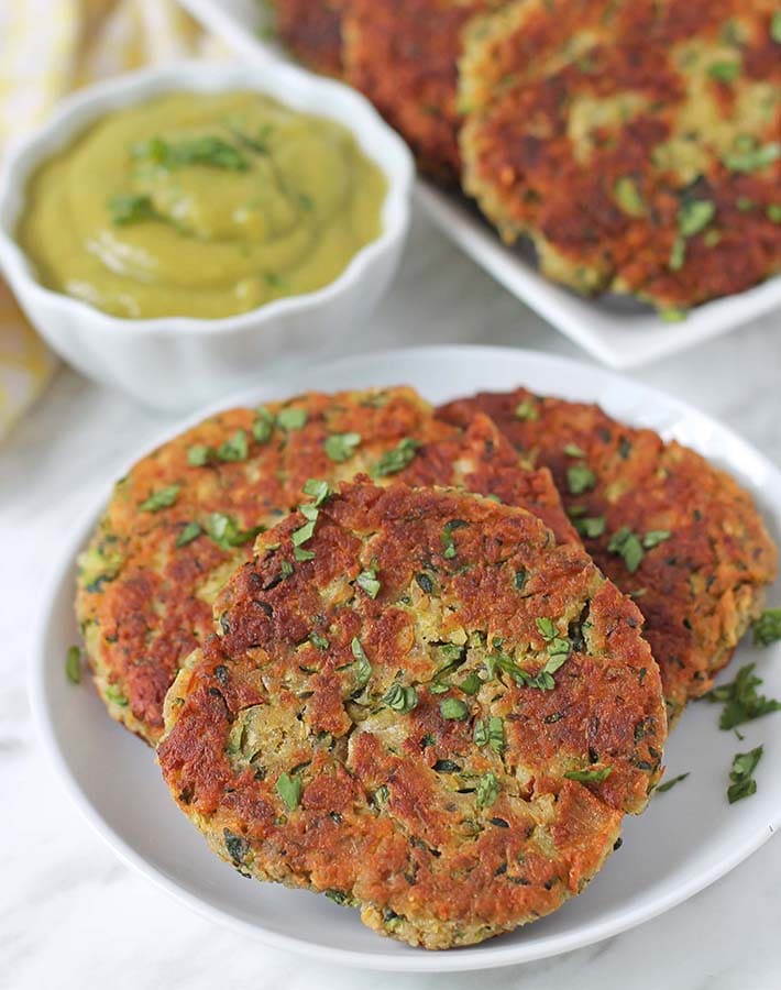Three egg free zucchini fritters on a plate.