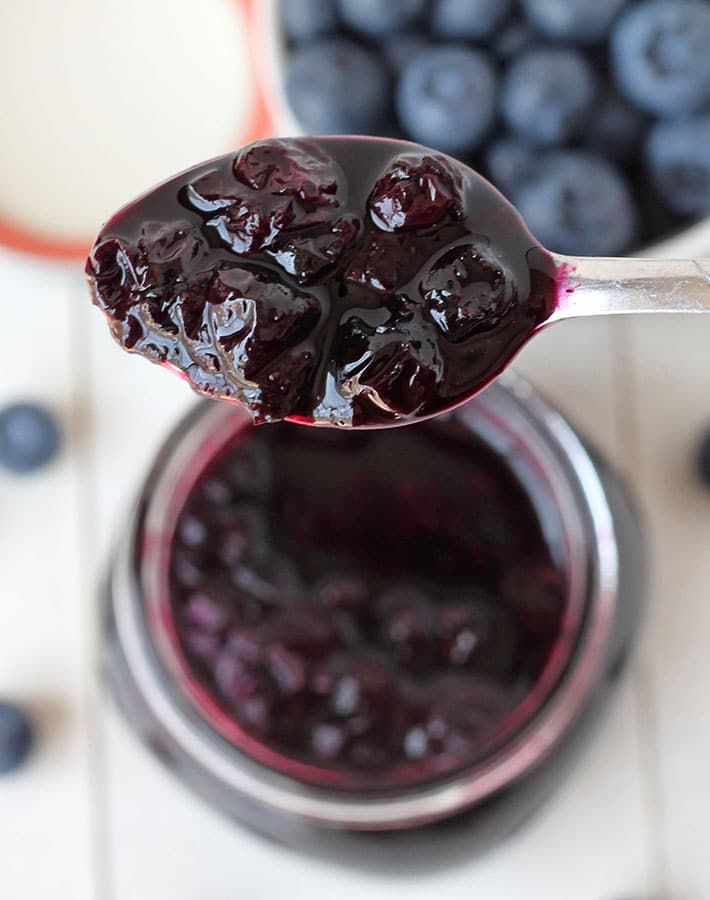 A spoonful of easy blueberry sauce over the jar of sauce.