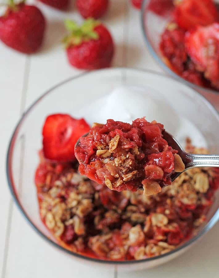 A close up shot of gf strawberry rhubarb crisp on a spoon.