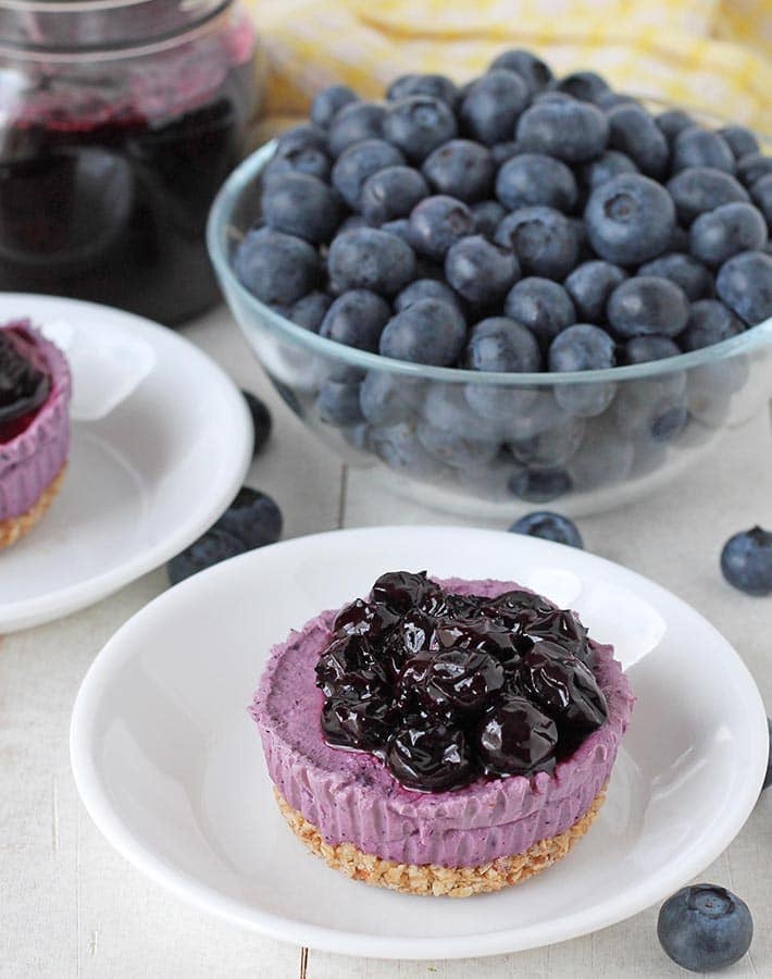 Mini vegan blueberry cheesecake topped with blueberry compote on a plate.