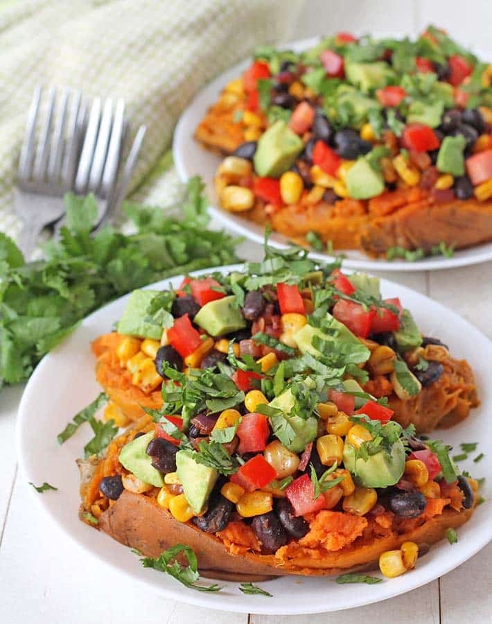 Two black bean stuffed sweet potatoes on a white plate.