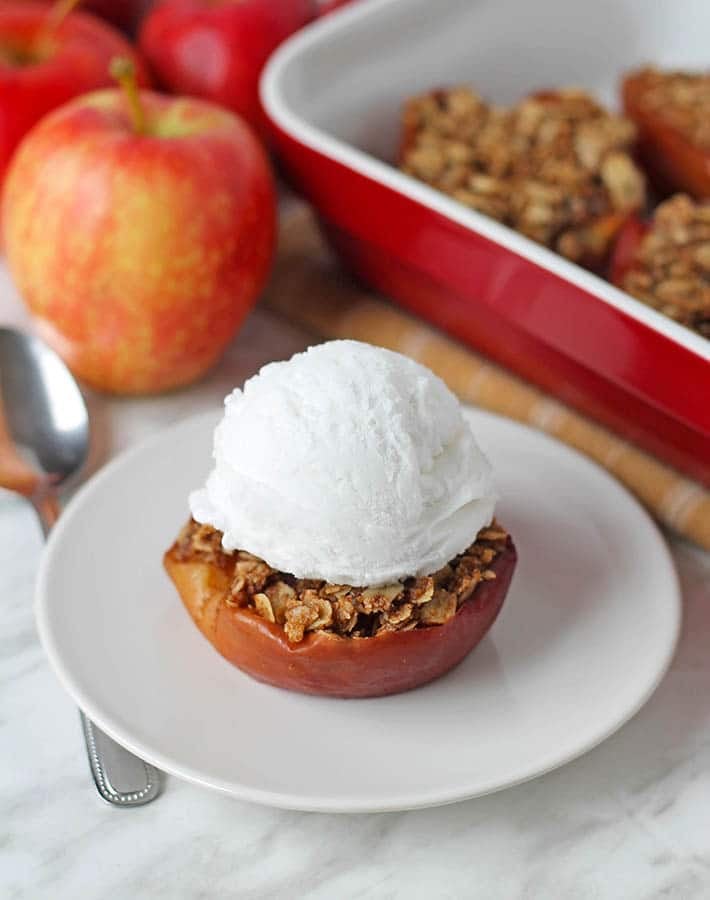 Oven baked apple half on a plate with ice cream on top.