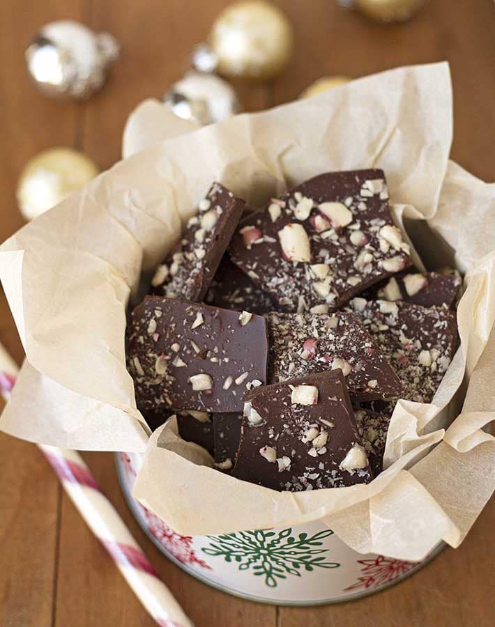 Pieces of dark chocolate peppermint bark in a small holiday tin.
