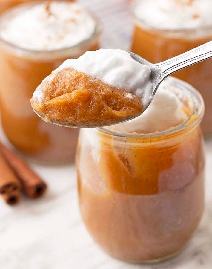 A spoon filled with vegan sweet potato pudding and coconut whipped cream.