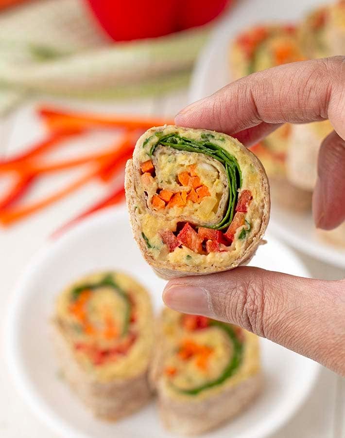 A hand holding a sliced pinwheel wrap to show it close up.