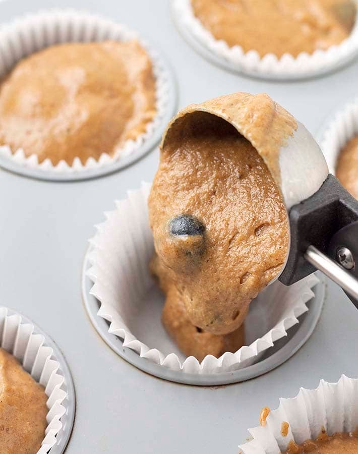 The batter for vegan gluten free banana blueberry muffins being scooped into a muffin cup.