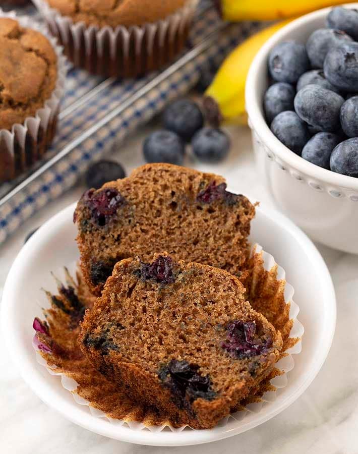 A banana blueberry gluten free muffin split in half on a small plate.