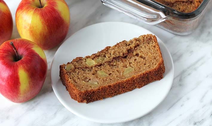 A slice of vegan applesauce bread on a small white plate.