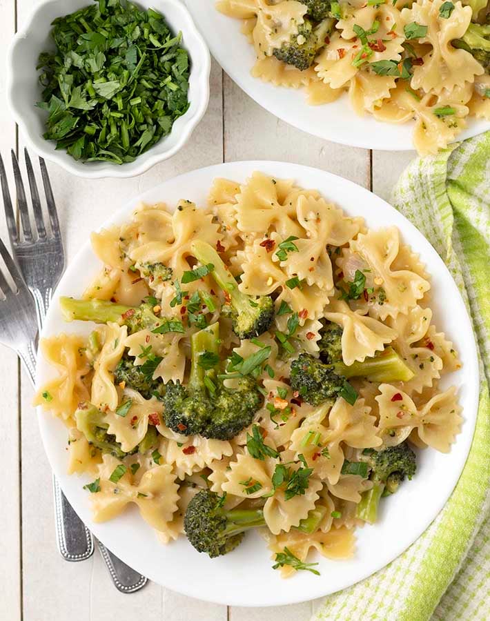 Overhead shot of a plate of creamy vegan broccoli pasta on a white plate.