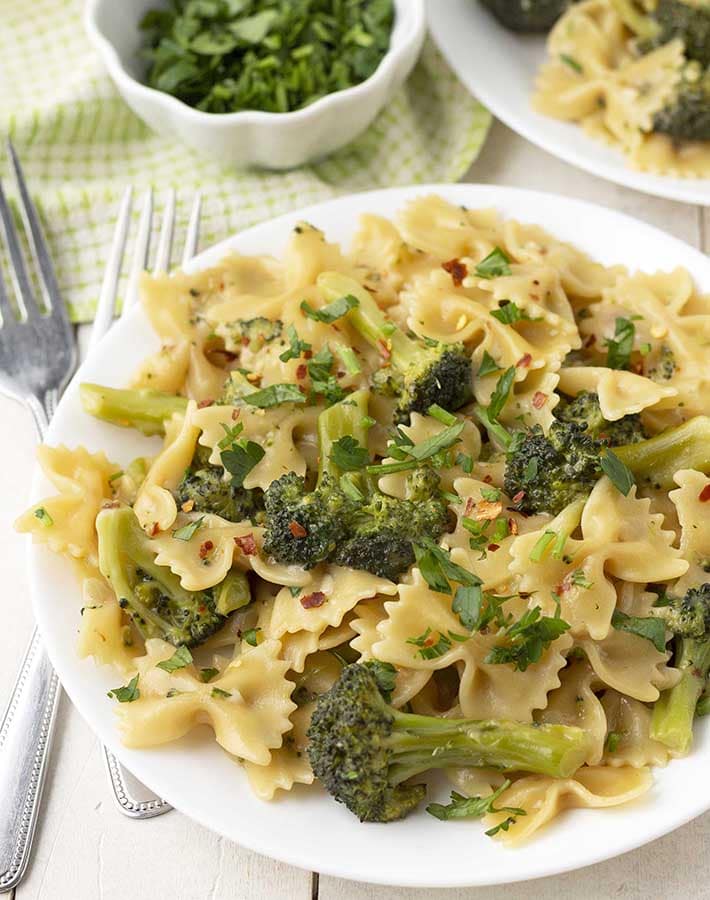 Close up shot of a plate of bow tie pasta with broccoli.