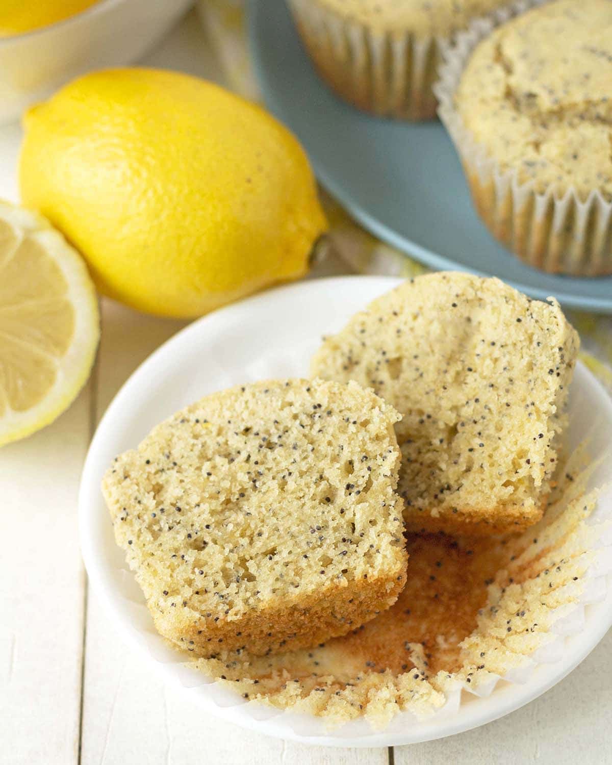 A split lemon poppy seed muffin on a plate showing the inner fluffy texture.