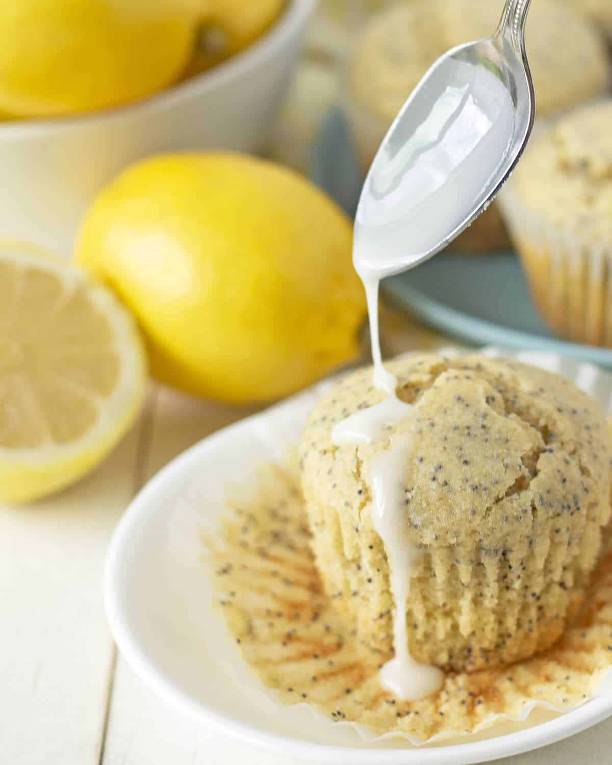 Lemon glaze being drizzled with a spoon onto a muffin.